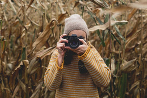 woman taking a picture wearing a yellow wool jumper